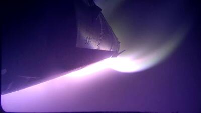 Underside of Starship (SpaceX) with purple plasma glow and bright plume lighting the hull against a dark sky.
