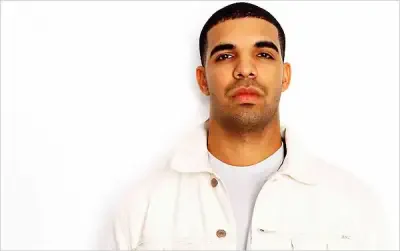 Head-and-shoulders portrait of a young man I can’t identify: short hair, trimmed beard, wearing a white jacket, neutral expression against a white background.