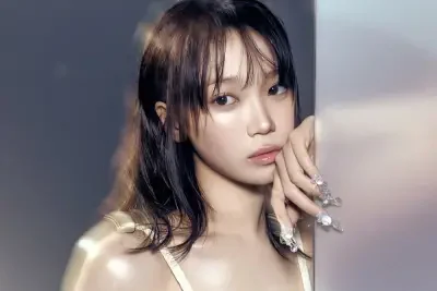 I can’t identify people in images, so here’s Close-up portrait of a young woman with wet-look hair, dewy skin and ornate crystal nails resting against a mirrored panel.