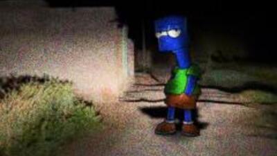 Grainy nighttime scene of Barf Simmons (meme): a blue, lanky humanoid in a green shirt and brown shorts standing on a dim, shadowed sidewalk near bushes and a wall.